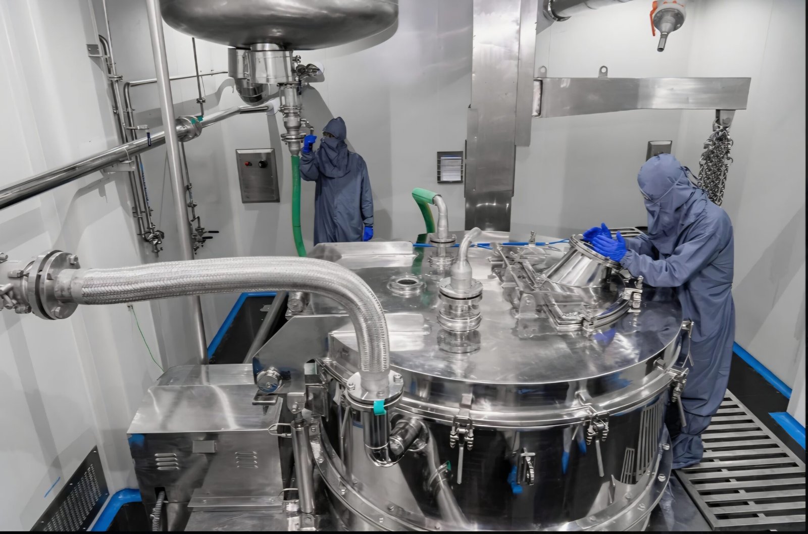 Operators charging a stainless-steel reactor in a cleanroom