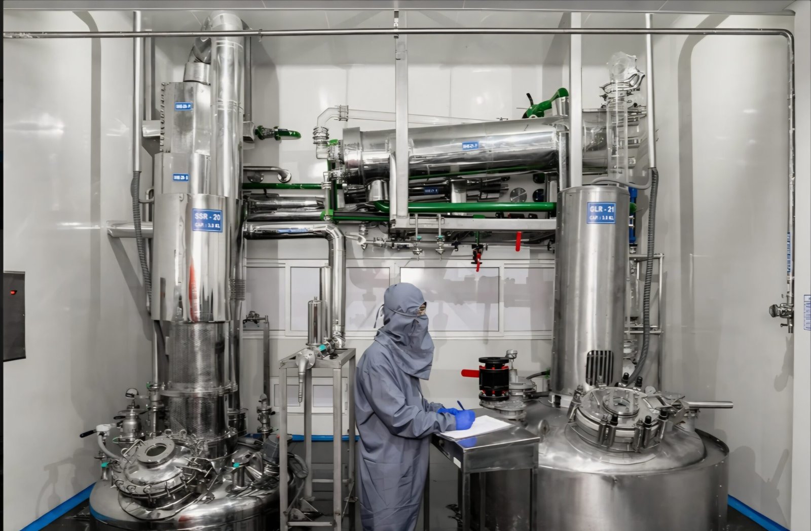 Scientist recording process data beside the reactors